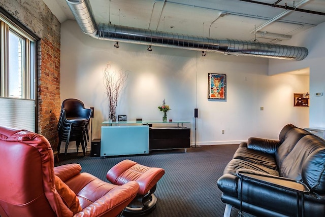 living room with brick wall and dark colored carpet