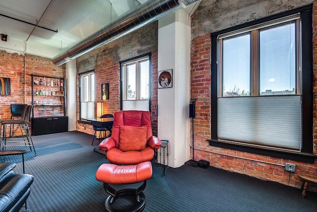 living area featuring carpet floors and brick wall