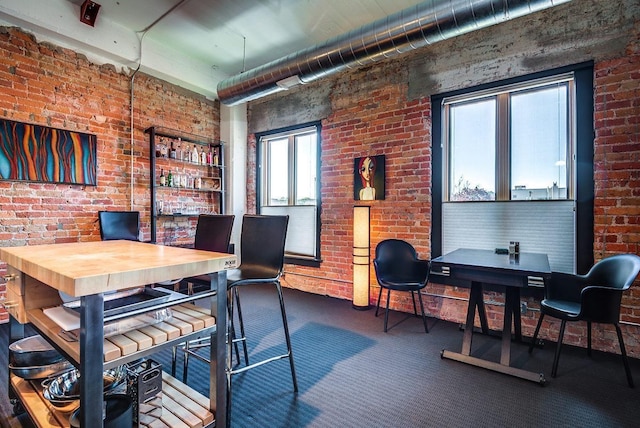 carpeted office space with brick wall