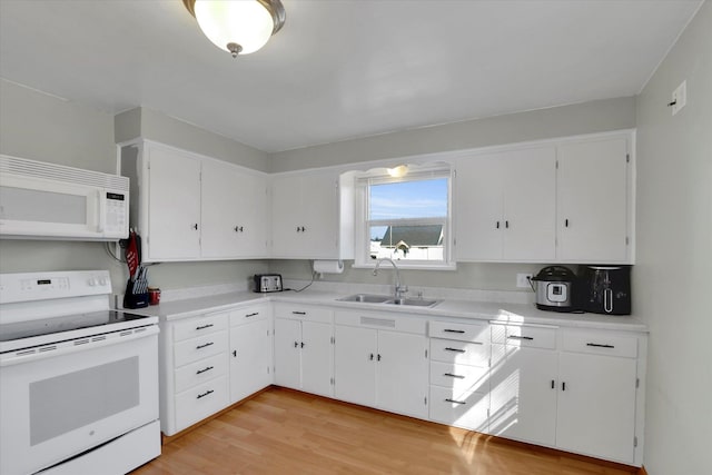 kitchen featuring white cabinets, white appliances, light wood-style floors, and a sink