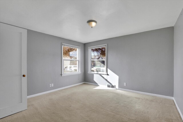 spare room featuring carpet, visible vents, and baseboards