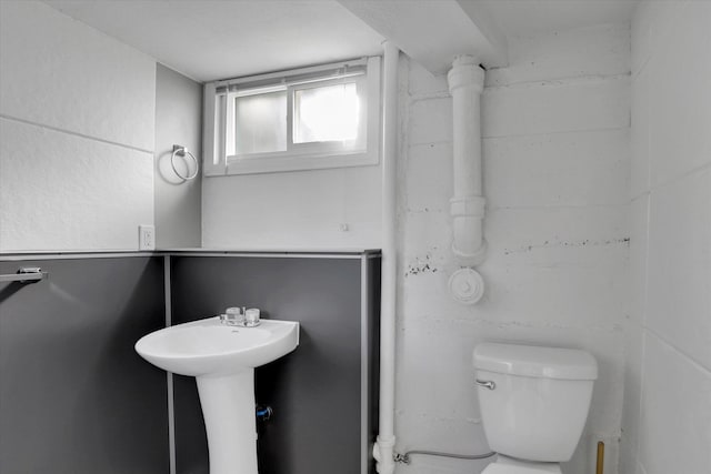 half bathroom with toilet and concrete block wall