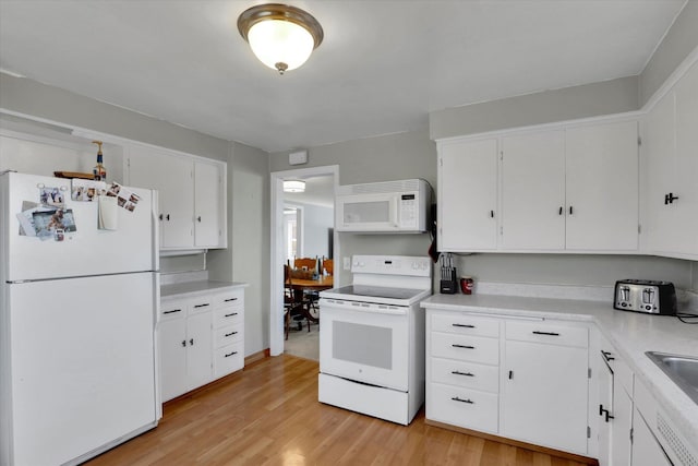 kitchen with white appliances, a sink, white cabinetry, light countertops, and light wood-type flooring