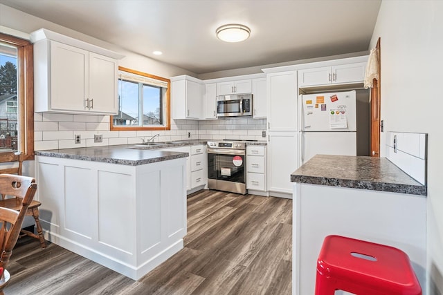 kitchen featuring white cabinetry, stainless steel appliances, dark hardwood / wood-style floors, and tasteful backsplash