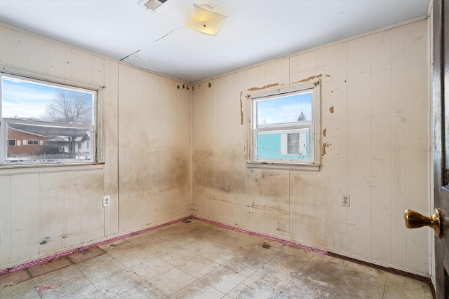 unfurnished room featuring wooden walls