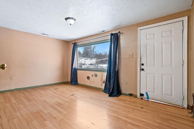 unfurnished room featuring light hardwood / wood-style flooring and a textured ceiling