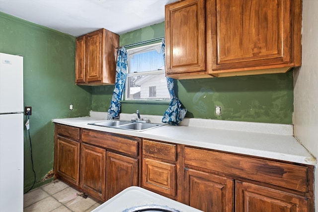 kitchen featuring white refrigerator, sink, and light tile patterned floors