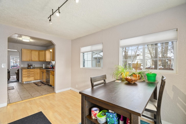 dining space with sink, track lighting, a textured ceiling, and light hardwood / wood-style floors