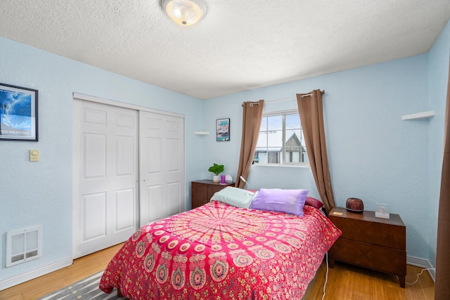 bedroom featuring hardwood / wood-style flooring, a textured ceiling, and a closet