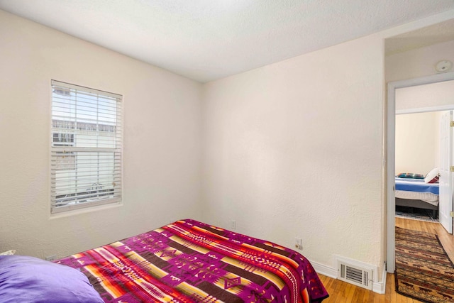 bedroom with a textured ceiling and light wood-type flooring