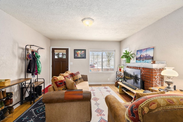 living room with a brick fireplace, light hardwood / wood-style floors, and a textured ceiling