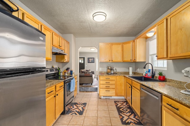 kitchen featuring stainless steel appliances, light stone countertops, sink, and light tile patterned floors