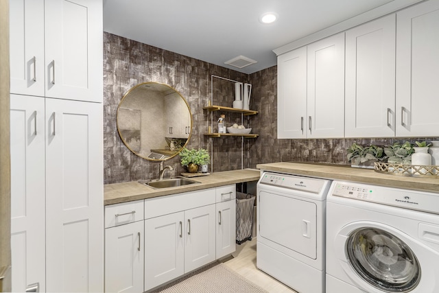 washroom with cabinets, separate washer and dryer, and sink