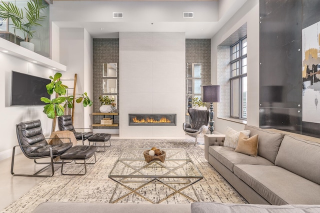 living room with a towering ceiling and a tile fireplace