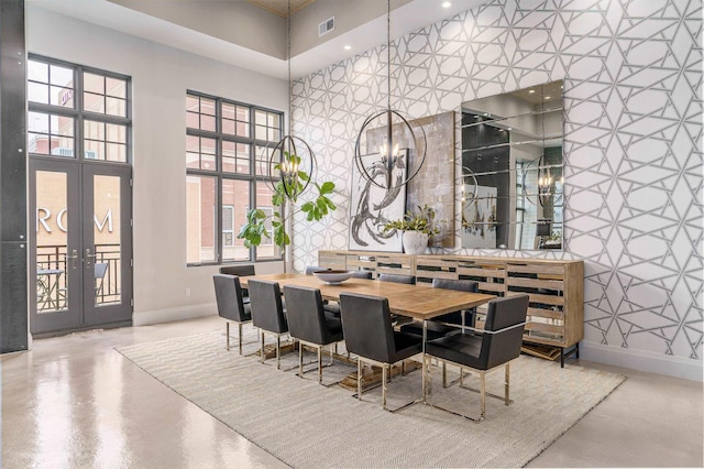 dining space with a towering ceiling, an inviting chandelier, and french doors