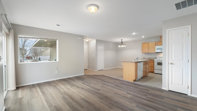 kitchen with a kitchen island, pendant lighting, a chandelier, light brown cabinets, and white appliances