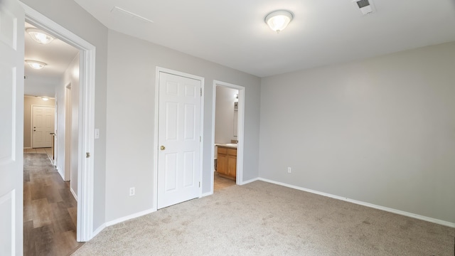 unfurnished bedroom featuring ensuite bath and light carpet