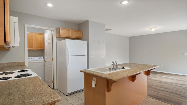 kitchen featuring sink, a kitchen breakfast bar, a center island, white refrigerator, and washer / dryer