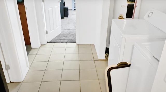 clothes washing area featuring light tile patterned floors and washing machine and dryer