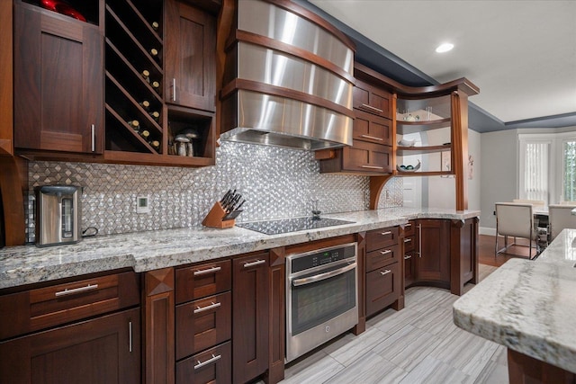 kitchen featuring oven, backsplash, black electric stovetop, exhaust hood, and light stone countertops