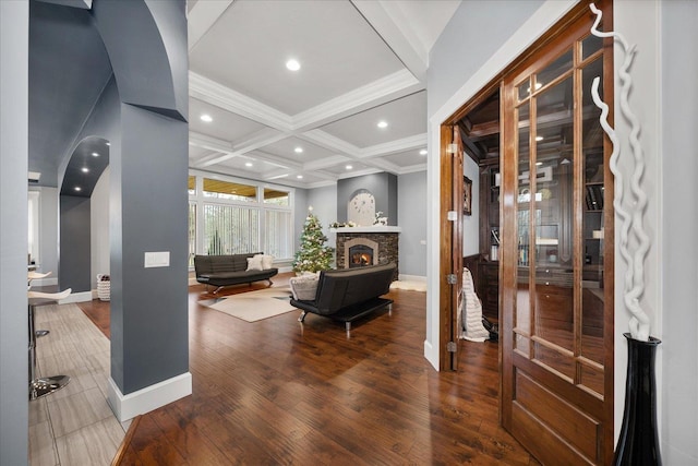 entryway featuring coffered ceiling, hardwood / wood-style floors, a stone fireplace, and beam ceiling