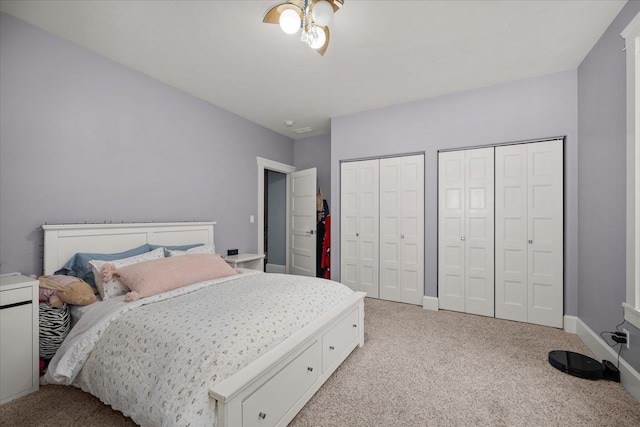 bedroom featuring light carpet and two closets