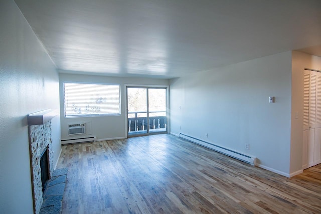 unfurnished living room with an AC wall unit, a fireplace, light hardwood / wood-style flooring, and a baseboard heating unit