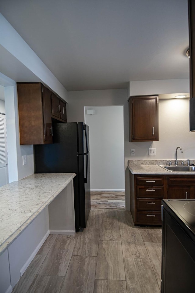 kitchen featuring sink, dark brown cabinetry, and black appliances