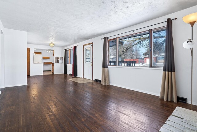 unfurnished living room with wood-type flooring, a textured ceiling, and wood walls