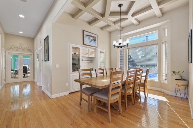 dining space with baseboards, a wealth of natural light, light wood-type flooring, and a towering ceiling