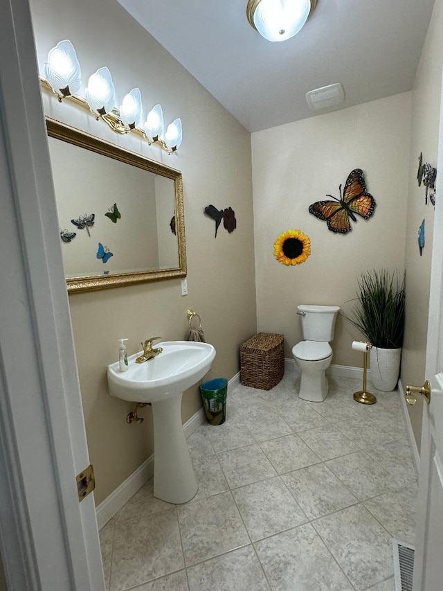 half bath featuring tile patterned floors, toilet, visible vents, and baseboards