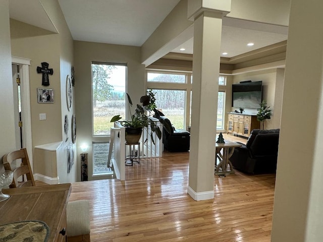 foyer with wood-type flooring, baseboards, and decorative columns