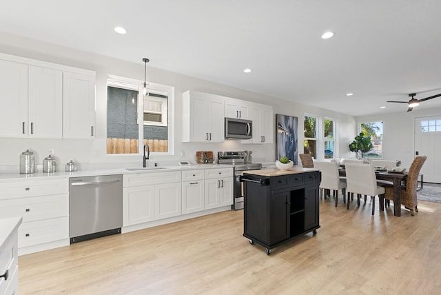 kitchen with stainless steel appliances, sink, pendant lighting, and white cabinets