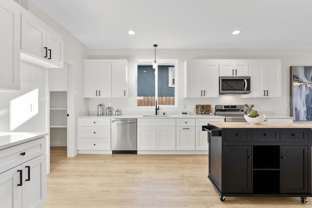 kitchen featuring stainless steel appliances, sink, pendant lighting, and white cabinets