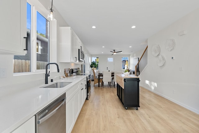 kitchen featuring pendant lighting, sink, appliances with stainless steel finishes, white cabinets, and light wood-type flooring