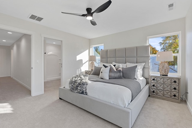 bedroom featuring ceiling fan, ensuite bathroom, and light carpet