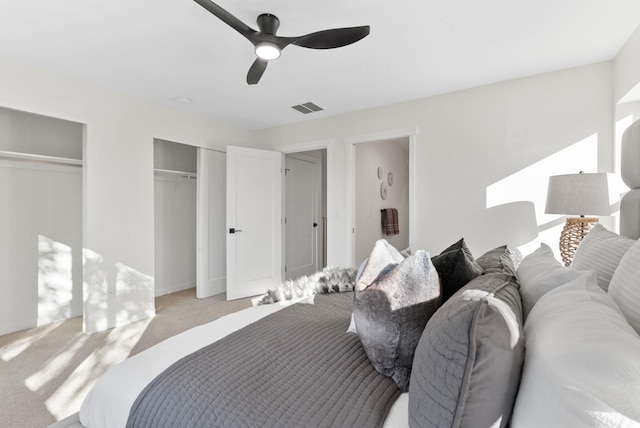 carpeted bedroom featuring multiple closets and ceiling fan