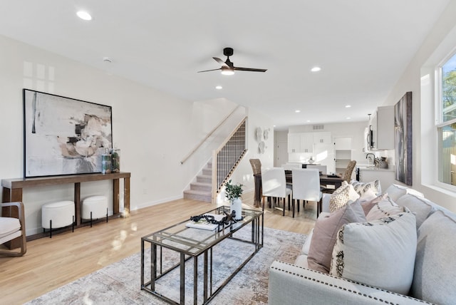 living room featuring sink, light hardwood / wood-style floors, and ceiling fan