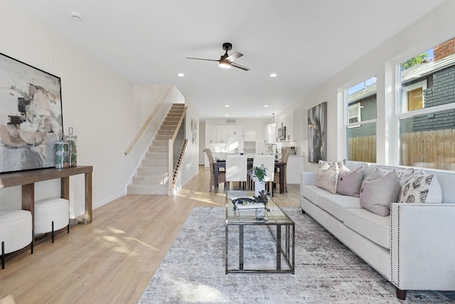 living room with sink, ceiling fan, and light wood-type flooring