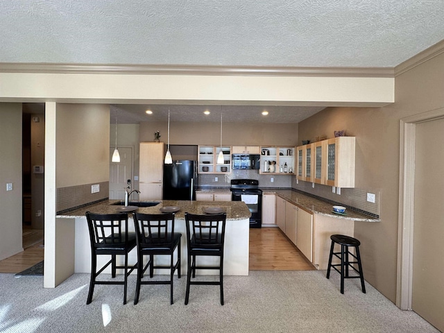 kitchen with a breakfast bar, decorative light fixtures, black appliances, sink, and kitchen peninsula