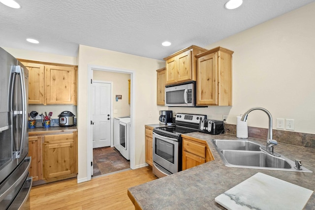 kitchen featuring sink, light hardwood / wood-style flooring, stainless steel appliances, and a textured ceiling