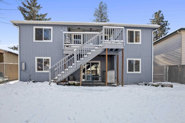 snow covered back of property with a deck