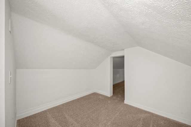 bonus room with vaulted ceiling, a textured ceiling, and carpet