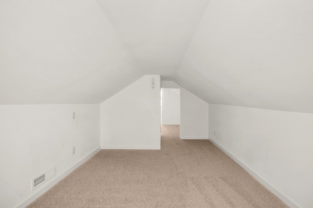 bonus room with vaulted ceiling and light carpet