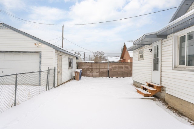 snowy yard with a garage and an outdoor structure