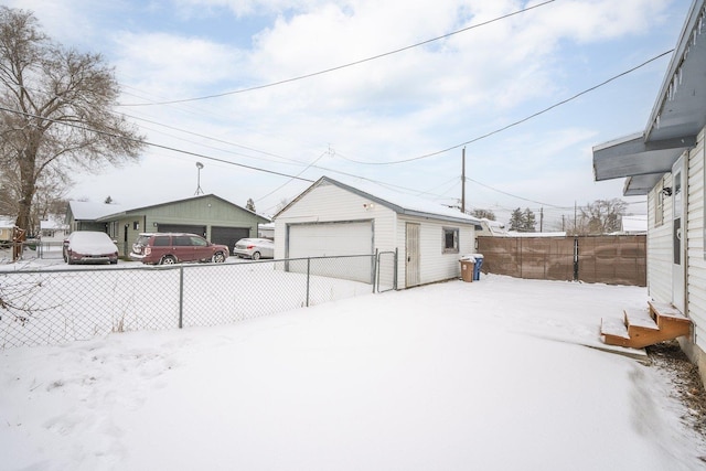 snowy yard with a garage and an outdoor structure