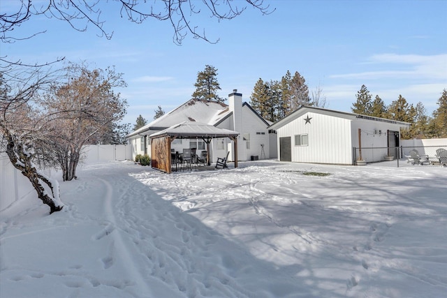 snow covered back of property featuring a gazebo