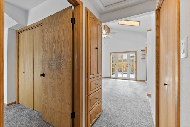 hall with vaulted ceiling, light carpet, and french doors