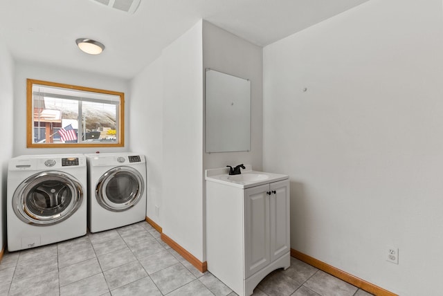 laundry room featuring light tile patterned flooring, cabinets, sink, and washer and dryer