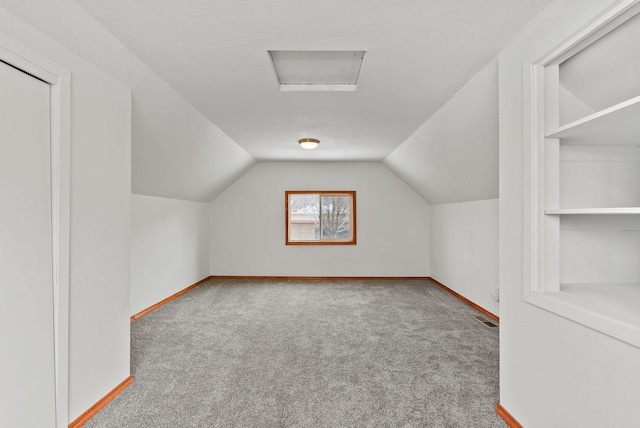 bonus room featuring lofted ceiling, carpet floors, built in features, and a textured ceiling